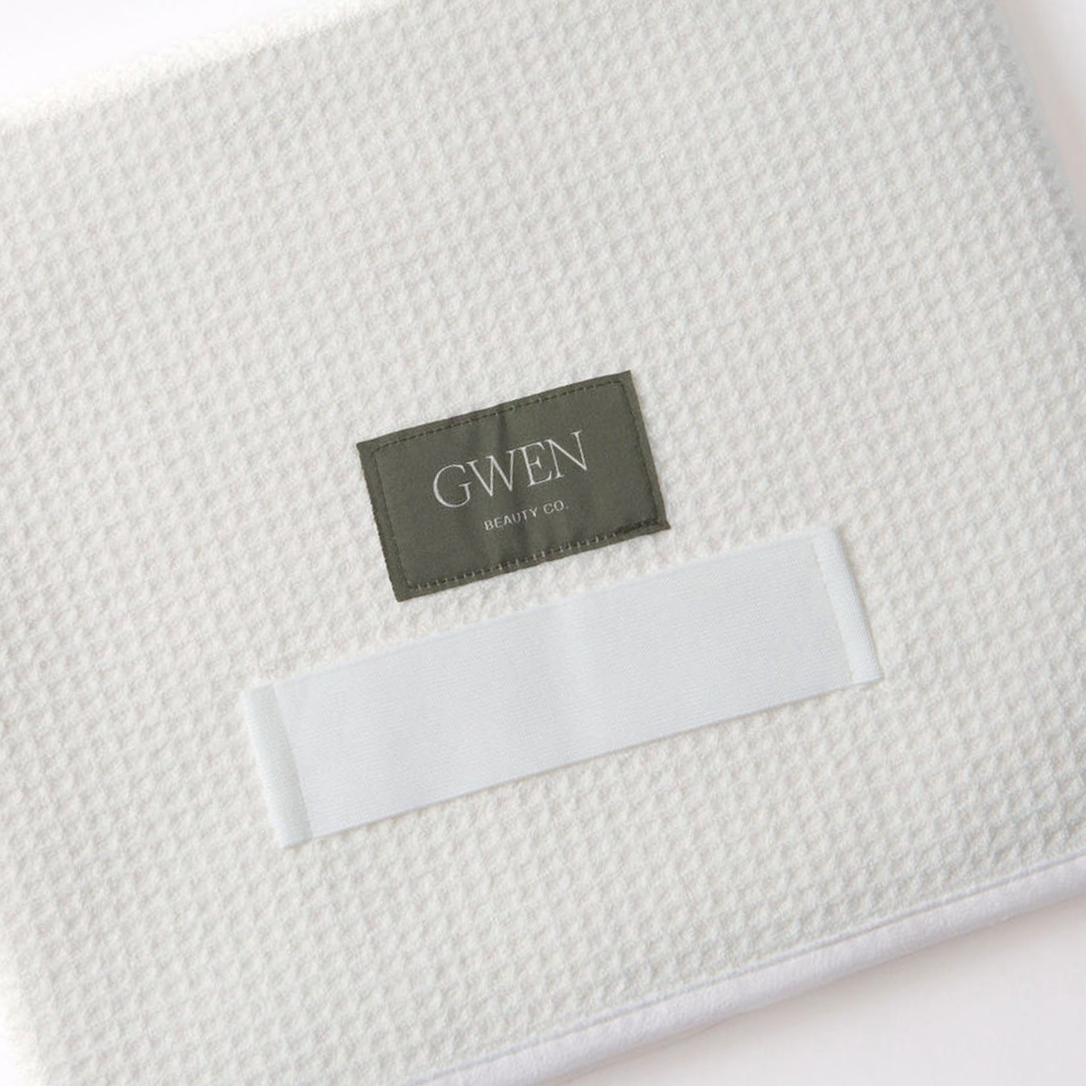The GWEN Hair Towel in Ivory laid flat at an angle, showing the waffle weave texture and the GWEN Beauty Co. label.
