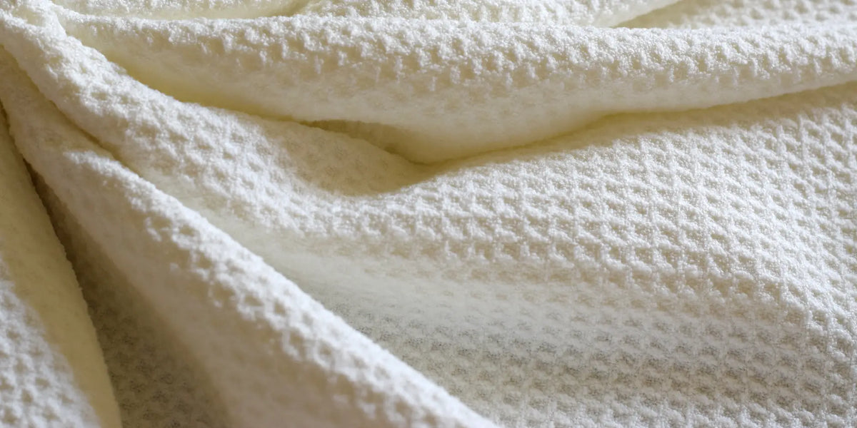 Close-up of the GWEN Hair Towel’s waffle weave microfiber fabric in Ivory, rippled to show texture.